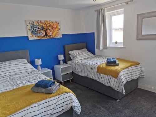 a bedroom with two beds and a blue wall at Modern Roomy 3 BR Home Pershore in Pershore