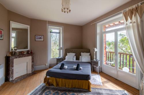 een slaapkamer met een bed, een open haard en ramen bij L'Écrin de Verdure - Pavillon avec piscine partagée in Thouars
