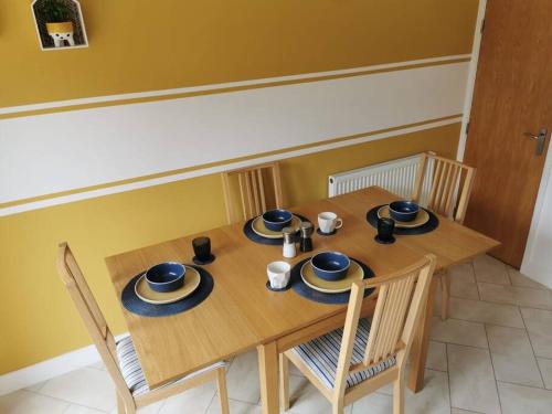 a wooden table with chairs and plates and cups on it at Modern Roomy 3 BR Home Pershore in Pershore