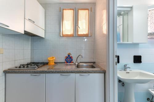 a white kitchen with a sink and a stove at Villa Oda - Monolocale sul mare in Capoliveri