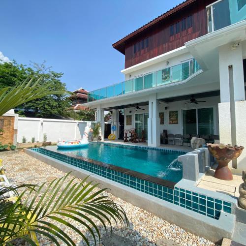 a house with a swimming pool in front of a house at Wan D Villa Pattaya in Jomtien Beach