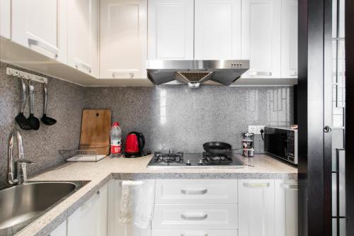 a kitchen with white cabinets and a stove top oven at Shanghai Art Decor Suite W Nanjing Rd FFC in Shanghai
