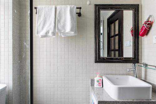 a white bathroom with a sink and a mirror at Shanghai Art Decor Suite W Nanjing Rd FFC in Shanghai