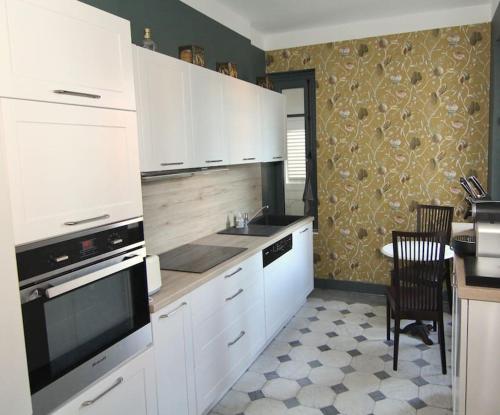 uma cozinha com armários brancos e uma mesa com mesa; em Location de Prestige : Duplex au Caractère Unique et Raffiné em Villefranche-sur-Saône