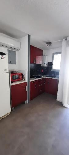 une cuisine avec des armoires rouges et un réfrigérateur blanc dans l'établissement Villa pinède - Proche naturiste, au Cap d'Agde