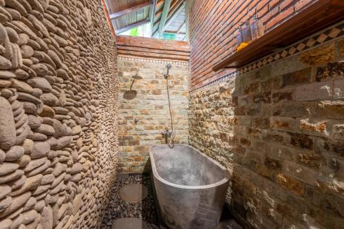 y baño con bañera en una pared de ladrillo. en Villa Pranawa, en Ubud