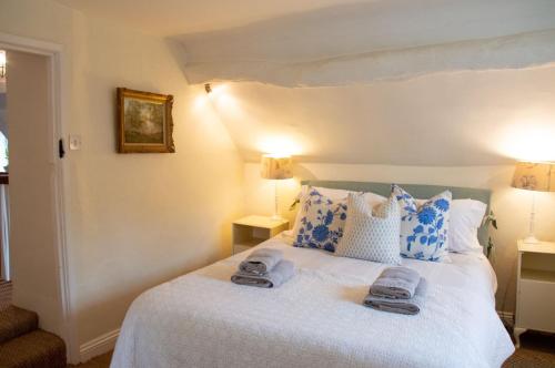 a bedroom with a bed with blue and white pillows at Top Cottage, Oddington in Adlestrop