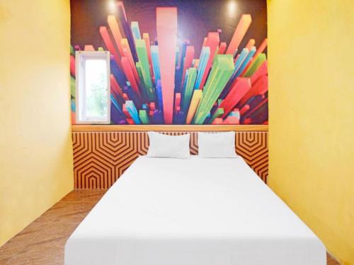 Cama en habitación con pared de plumas de colores en Wisma Pelangi Palopo RedPartner, en Palopo