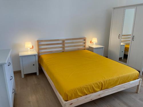 een slaapkamer met een geel bed en 2 nachtkastjes bij Appartamento Anemone in Termoli