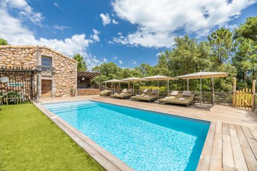 a pool with chairs and umbrellas next to a house at Hôtel du Domaine Casanghjulina in Porto-Vecchio