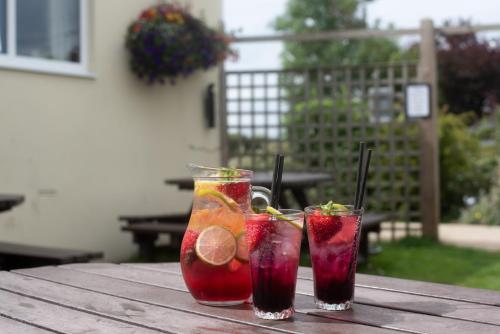 two cocktails on a wooden table with fruit on it at The Lindisfarne Inn - The Inn Collection Group in Beal