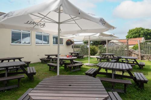 a group of picnic tables with an umbrella at The Lindisfarne Inn - The Inn Collection Group in Beal