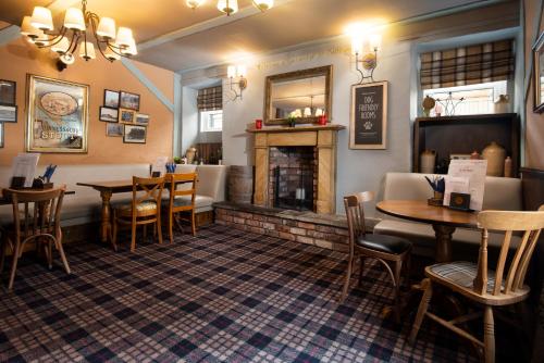 a restaurant with tables and chairs and a fireplace at The Lindisfarne Inn - The Inn Collection Group in Beal