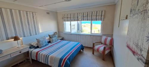 布菲尔斯巴埃Sailaway Beach House的一间卧室，里面有一张床、一把椅子和一扇窗户