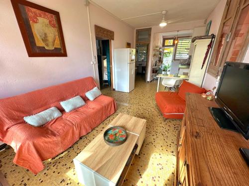 Una sala de estar con un sofá naranja y una mesa. en Kaz'Azula, en Saint-François