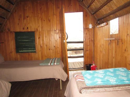 a room with two beds in a wooden cabin at Forest Cabin at Loodswaai between Dinokeng and Cullinan 