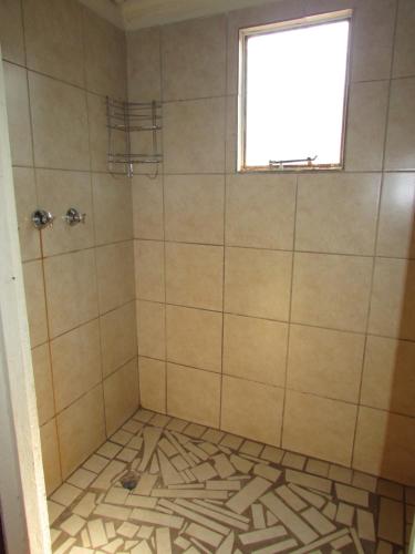a shower with a tiled floor and a window at Forest Cabin at Loodswaai between Dinokeng and Cullinan 