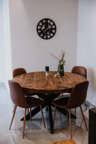 a dining room table with chairs and a clock on the wall at Pearl Apartel in Volos