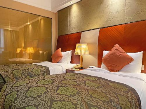 um quarto de hotel com duas camas e duas lâmpadas em Merry Hotel Shanghai (Former Rendezvous Merry Hotel Shanghai) em Xangai