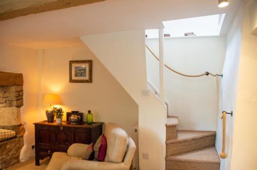 sala de estar con escaleras y silla en Top Cottage, Oddington, en Adlestrop