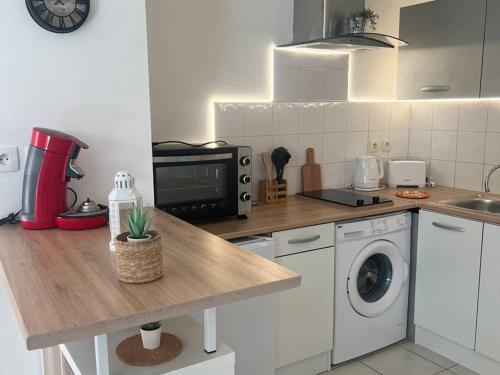 - une cuisine avec un comptoir et un lave-linge dans l'établissement Appartement T2 confortable à Cambo-les-Bains - Terrasse, Parking, Animaux Ok, Internet - FR-1-495-128, à Cambo-les-Bains