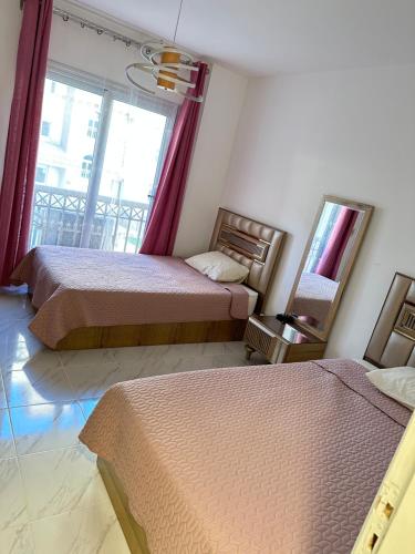 a bedroom with two beds and a mirror and a window at شقة فندقية جديدة في مدينتي in Cairo