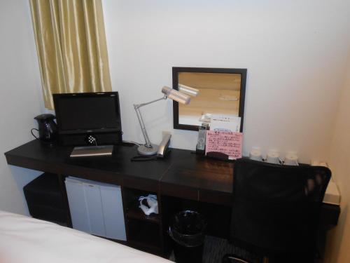 a desk in a hotel room with a bed and a lamp at Business Hotel Sunpu in Shizuoka