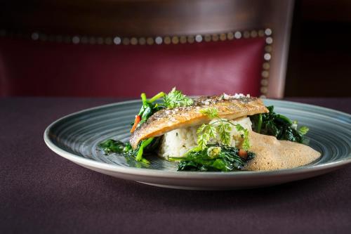 a plate of food with fish and greens on a table at Hotel Christiania in La Clusaz