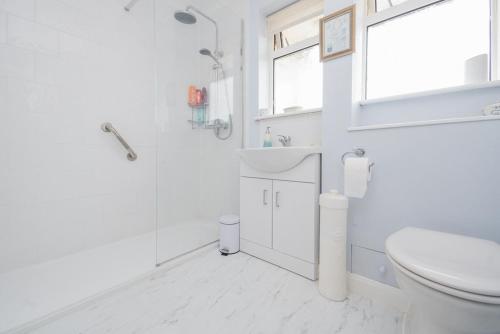 a white bathroom with a sink and a toilet at Amazing Beachside 2BD Family Home with Garden in Cliftonville