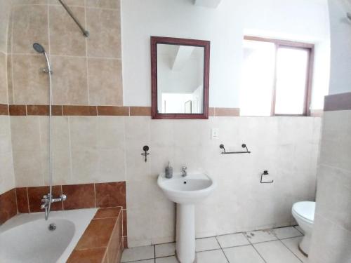 La salle de bains est pourvue d'un lavabo, d'une baignoire et de toilettes. dans l'établissement The Freshwater Pearl, à Pretoria