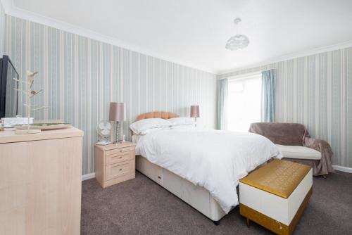 a bedroom with a bed and a chair and a window at Amazing Beachside 2BD Family Home with Garden in Cliftonville