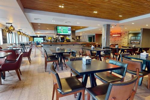 a restaurant with tables and chairs and a bar at Village Hotel Cardiff in Cardiff