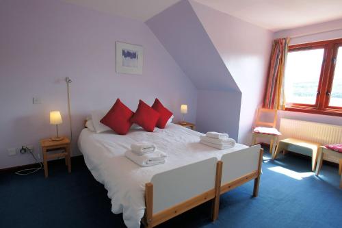a bedroom with a large white bed with red pillows at Osprey View in Lochearnhead