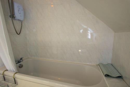 a white bathroom with a tub and a shower at Osprey View in Lochearnhead