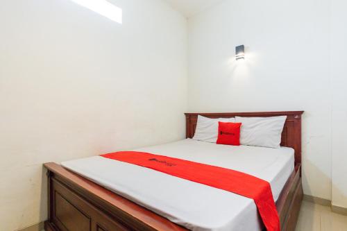 a bedroom with a bed with a red blanket on it at RedDoorz @ Raya Ngagel 2 in Surabaya