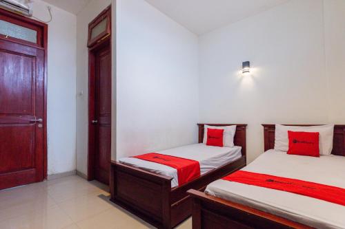 una camera con 2 letti con cuscini rossi di RedDoorz @ Raya Ngagel 2 a Surabaya