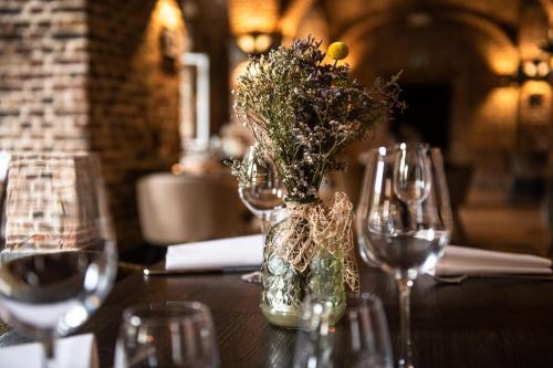 a table with wine glasses and a vase with flowers at Mercure Liege City Centre in Liège