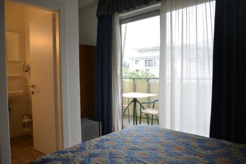 a bedroom with a bed and a window with a table at Hotel Primo in Riva del Garda