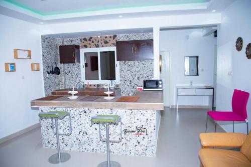 a kitchen with a counter and pink bar stools at CAB LFS SIPRES MOURTADA 3e ETAGE in Dakar