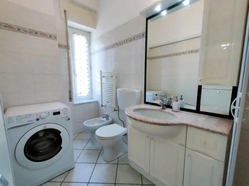 baño blanco con lavadora y lavamanos en Brezza d'Estate - L'Opera Group, en La Spezia