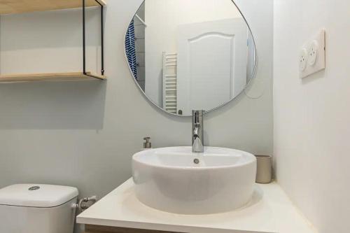 une salle de bain blanche avec un lavabo et un miroir dans l'établissement Baussenque - Bel appartement au coeur du Panier, à Marseille