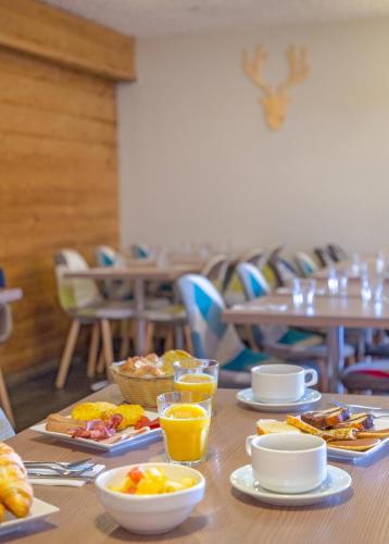 Una mesa cubierta con platos de comida y vasos de jugo de naranja. en SOWELL HOTELS Le Pas du Loup, en Isola 2000