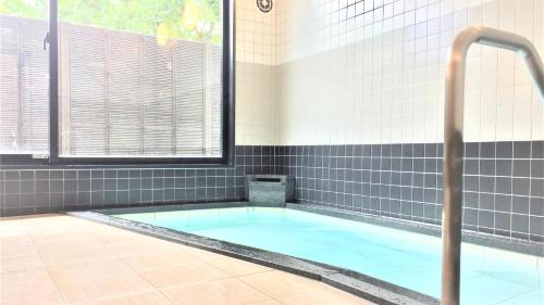 a bathroom with a hot tub with a window at Murayama Nishiguchi Hotel in Murayama