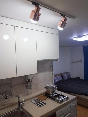a kitchen with a sink and white cabinets and a bed at Changdong Property in Seoul