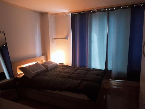 a bedroom with a bed with a lamp and blue curtains at Changdong Property in Seoul