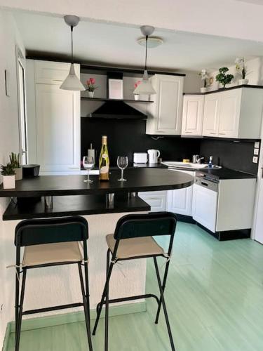 une cuisine avec deux chaises, une table et un comptoir dans l'établissement Springfields - Appart en résidence proche du parlement européen, à Schiltigheim