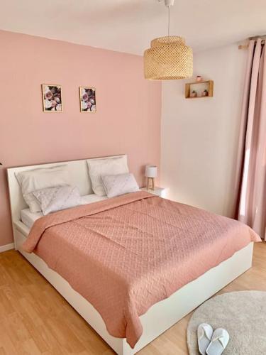 une chambre avec un grand lit avec une couverture rose dans l'établissement Springfields - Appart en résidence proche du parlement européen, à Schiltigheim