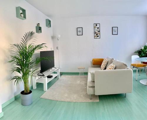 un salon avec un canapé blanc et une plante dans l'établissement Springfields - Appart en résidence proche du parlement européen, à Schiltigheim
