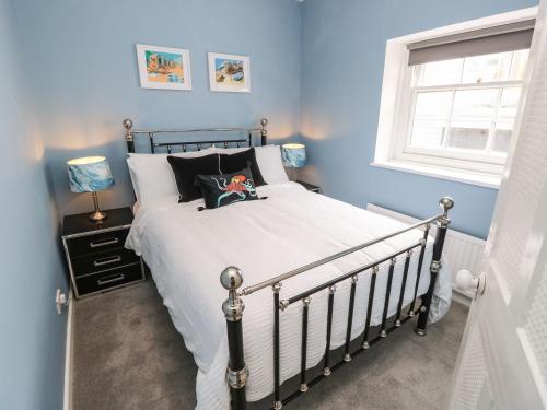 a bedroom with a bed with a blue wall at Riverdance Cottage in Lyme Regis