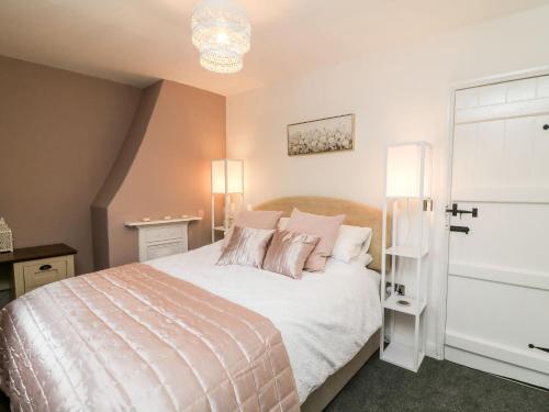 um quarto com uma cama grande e almofadas cor-de-rosa em 2 Morton Cottages em Preston